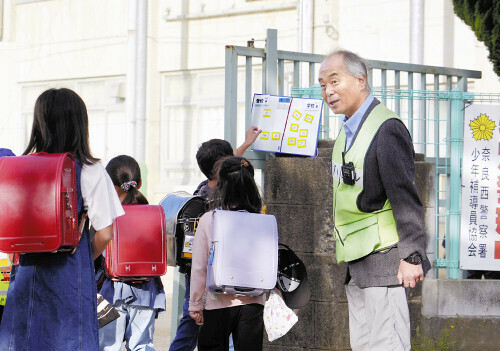 児童の登校を見守る後藤校長（右）（６日、奈良市で）＝浜井孝幸撮影