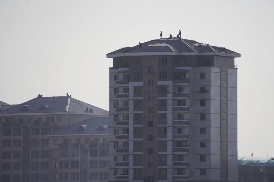 北朝鮮・新義州で建設中の高層住宅の屋根で作業する労働者＝28日、中国・丹東から撮影（共同）