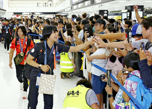 パリ五輪から帰国し、到着ロビーに詰めかけた人たちの声援に応えるレスリングの藤波朱理選手（手前）ら（８月１３日午後、成田空港で）＝桐山弘太撮影