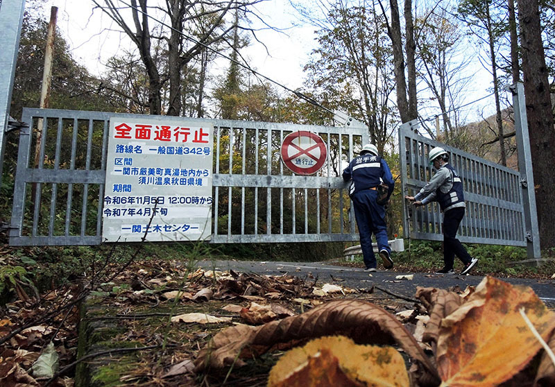 落ち葉に覆われた国道342号の真湯ゲートを閉じる一関土木センター職員＝5日正午、一関市厳美町