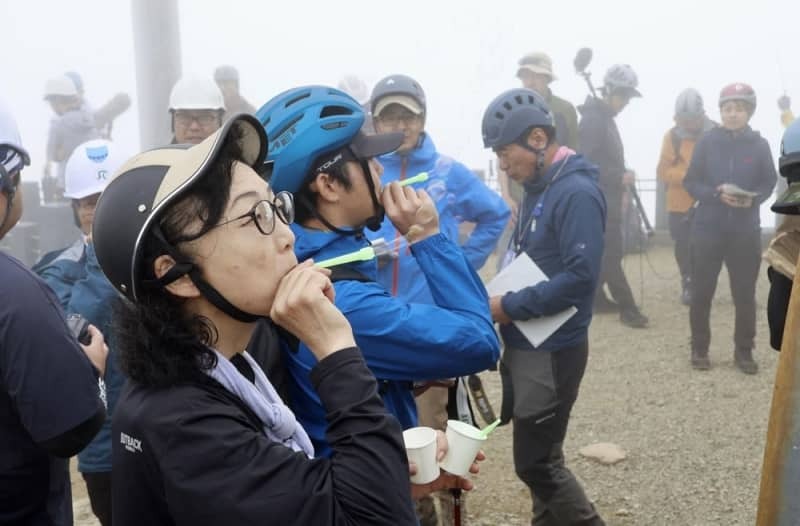 ⑧慰霊登山でシャボン玉を飛ばすシャーロック英子さん（手前）＝２０２４年７月２８日