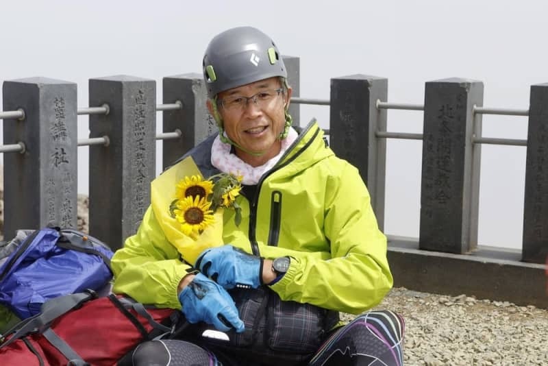 慰霊のため御嶽山に登り、ヒマワリの花束を抱える所清和さん＝２０２４年７月２８日