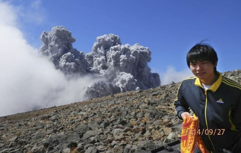 野村正則さんが撮影した亮太さん。後方は御嶽山噴火の噴煙＝２０１４年９月２７日（亮太さんの父敏明さん提供）