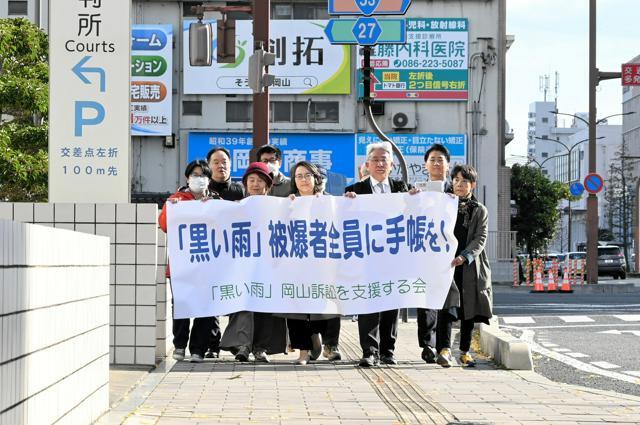 提訴に先立ち、横断幕を持って行進する弁護士や支援者ら=2024年11月29日午前9時54分、岡山市北区、北村浩貴撮影