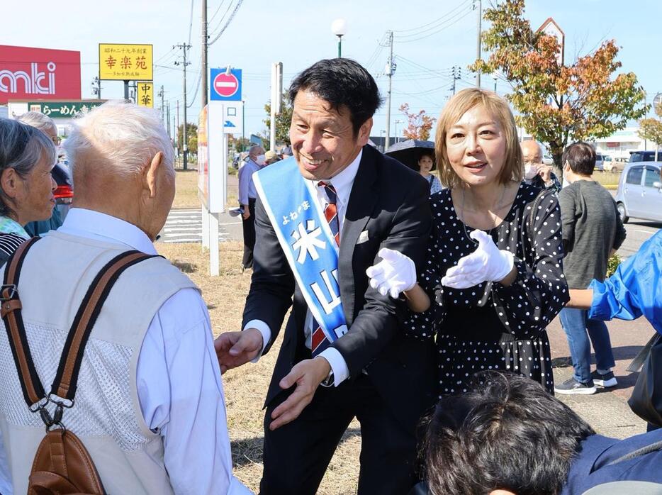 街頭演説に集まった有権者に握手をして回る米山隆一（中央）と妻の室井佑月（右隣）＝１０月１８日、見附市