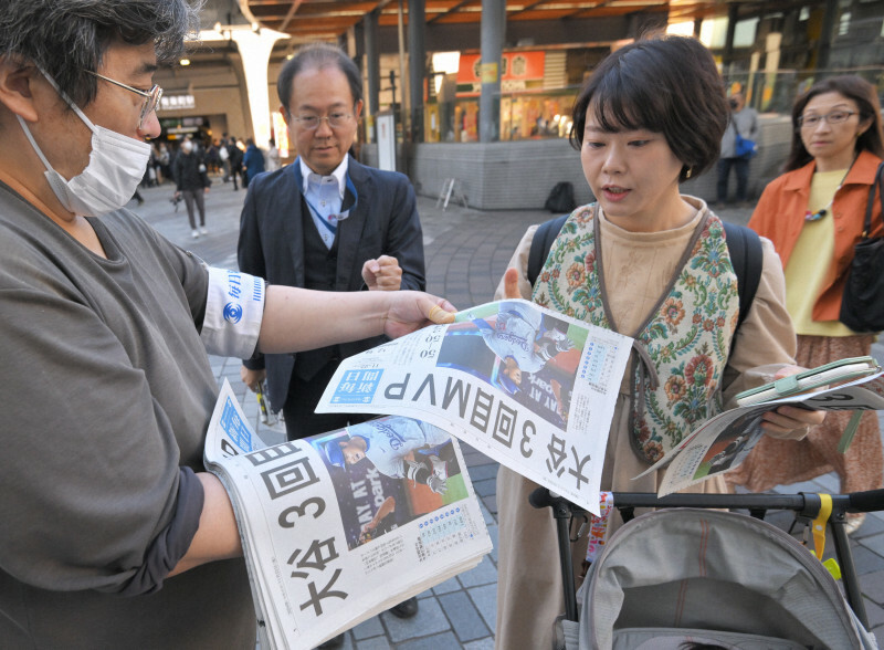 大谷翔平選手が2年連続3度目のMVPに選ばれ、街頭で配られる毎日新聞の号外を手にする人たち＝東京都千代田区のJR有楽町駅前で2024年11月22日午前11時6分、手塚耕一郎撮影