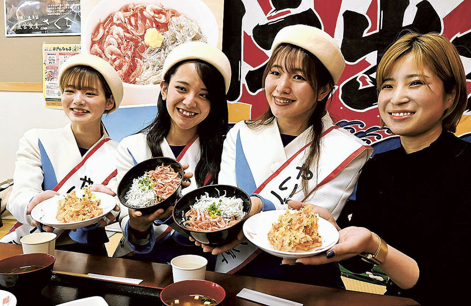 「おおいがわ桜えびめぐり」のメニューの一つとなる大井川みなと丼定食を手にする岩崎さん（右端）とやいづマリンレディの3人＝焼津市の大井川港漁協直営食堂さくら