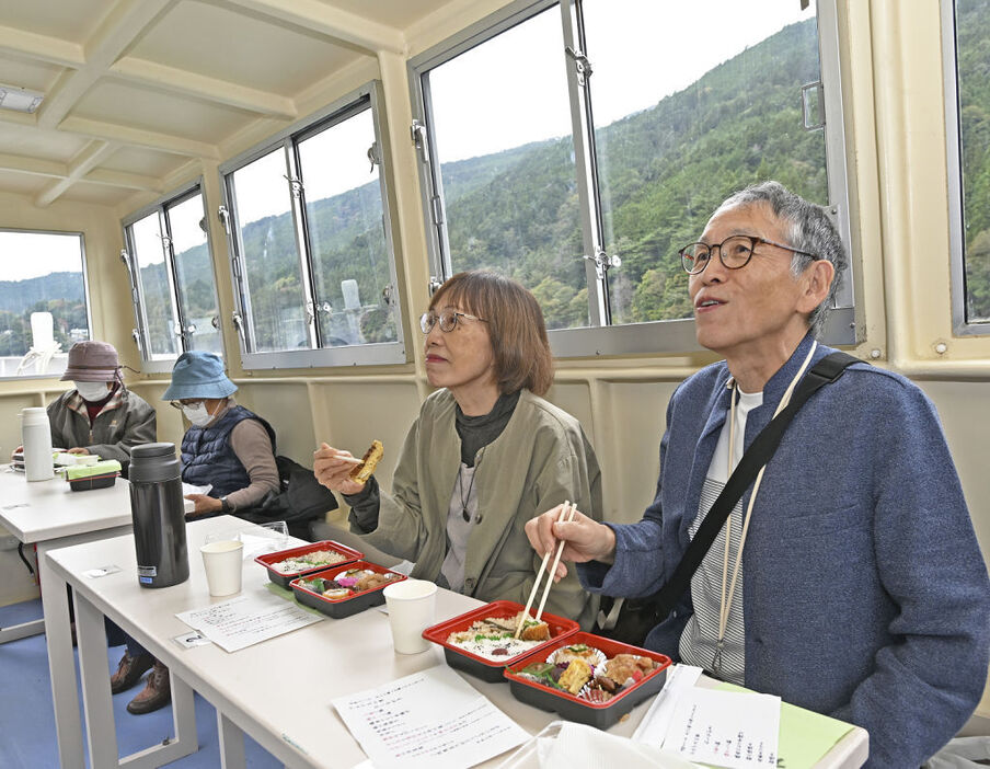 窓から見える風景を見ながら弁当を楽しむ乗船客＝静岡市葵区の井川湖