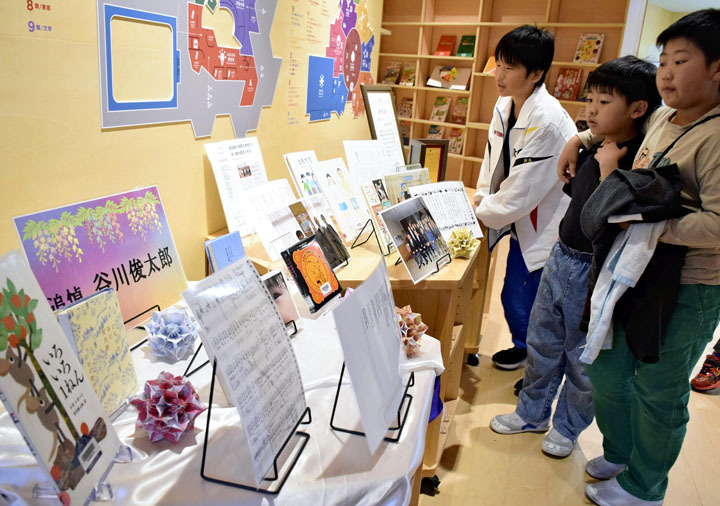 谷川さんの追悼コーナーで、学校とのつながりを示す資料などに見入る子どもたち＝大熊町・学び舎ゆめの森