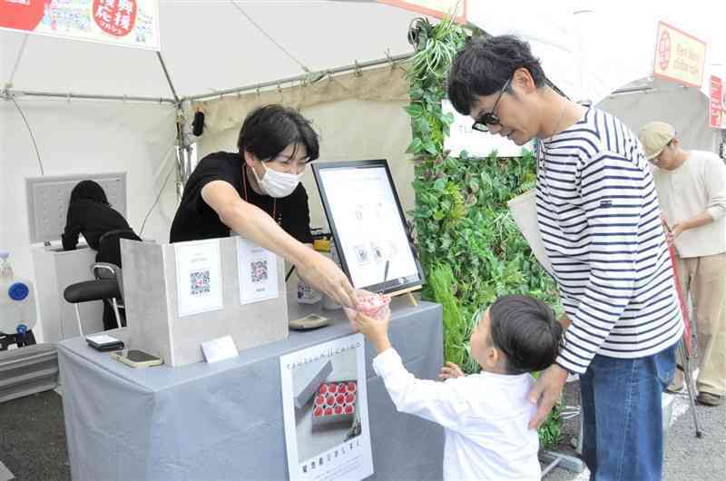 「くまもと復興応援マルシェ」で、冷凍イチゴを削ったスイーツを買う親子連れ＝15日、益城町