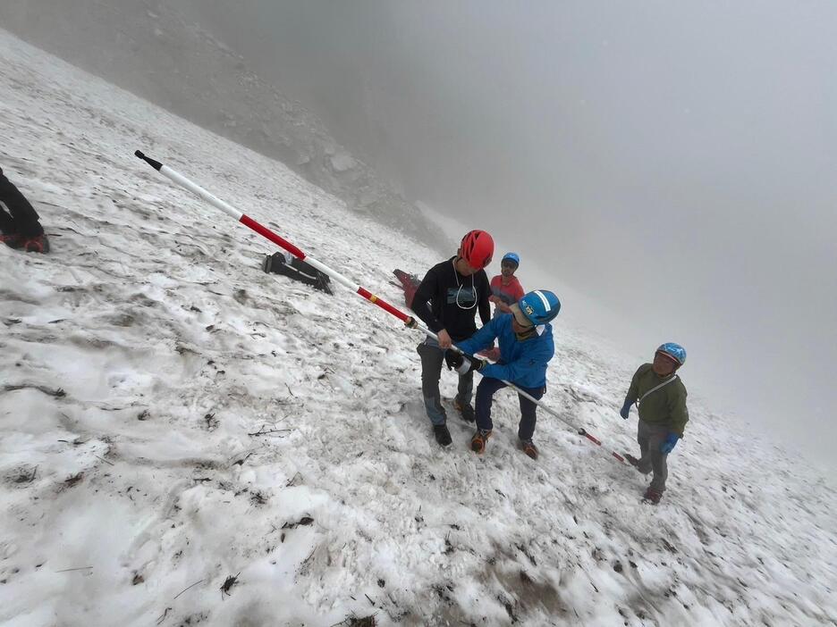 白馬沢の雪渓の動きを調べる白馬連山氷河調査団の団員ら＝8月8日、白馬村（同調査団提供）