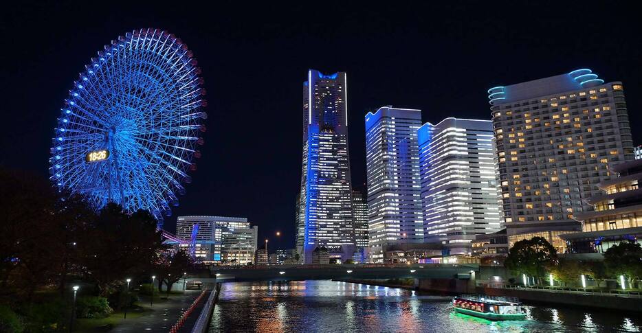 ベイスターズカラーの青色にライトアップされた大観覧車とみなとみらいの高層ビル＝横浜市西区