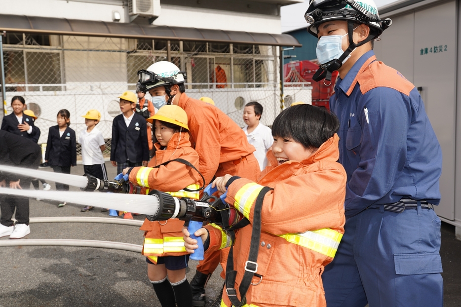 消防署員に支えてもらいながら放水を体験する児童たち＝兵庫県丹波篠山市北で