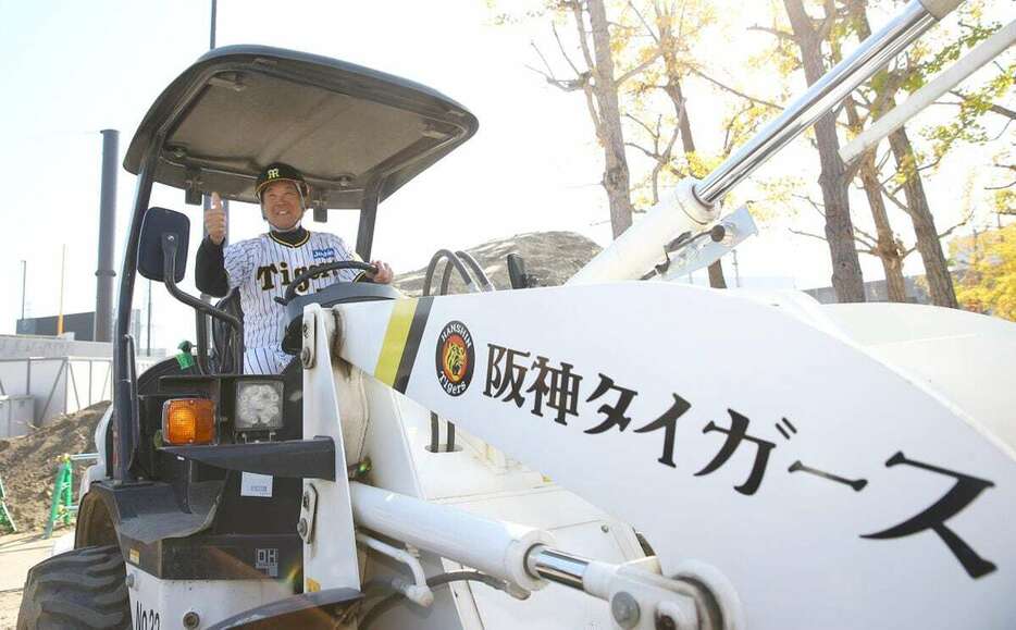 タイガースのロゴの入ったショベルカーに乗って写真に納まる阪神・平田勝男2軍監督＝日鉄鋼板SGLスタジアム（撮影・斉藤友也）