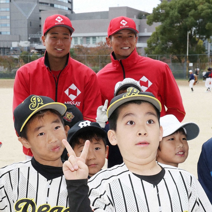 子どもたちと記念写真に納まる中日ドラフト4位の石伊（左）とロッテドラフト6位の立松（撮影・長嶋　久樹）