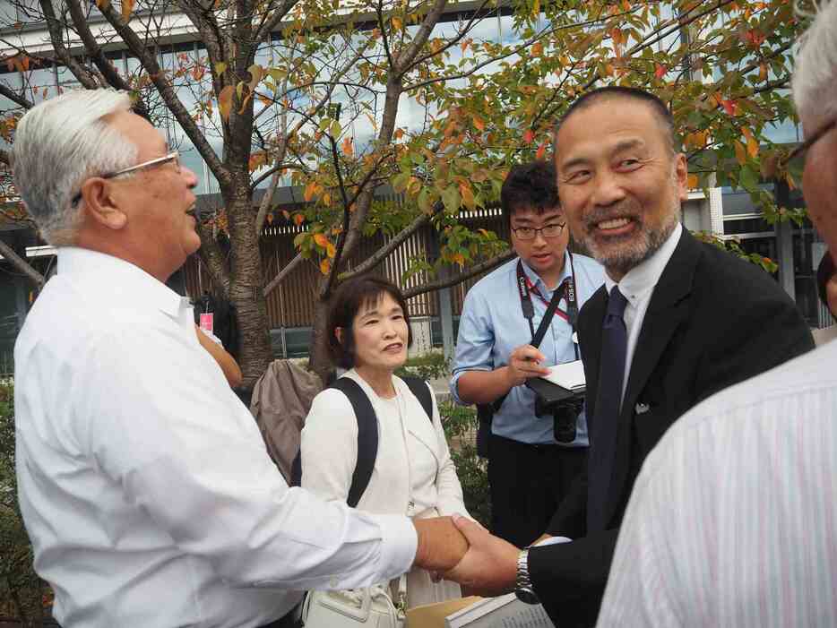 10月23日、冤罪被害者の遺族らと喜び合う前川彰司さん（右）　撮影・粟野仁雄