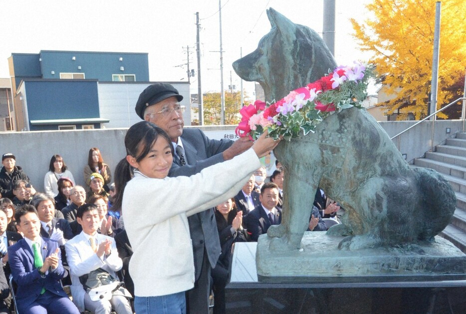 ハチ公の銅像に献花する地元の児童とハチ公生家の当主、斎藤良作さん＝秋田県大館市で2024年11月10日、田村彦志撮影