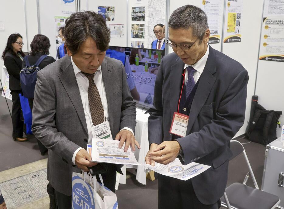 名古屋市で開かれた防災展で来場者（左）に説明する東日本大震災時に宮城県警本部長だった竹内直人さん＝29日午後