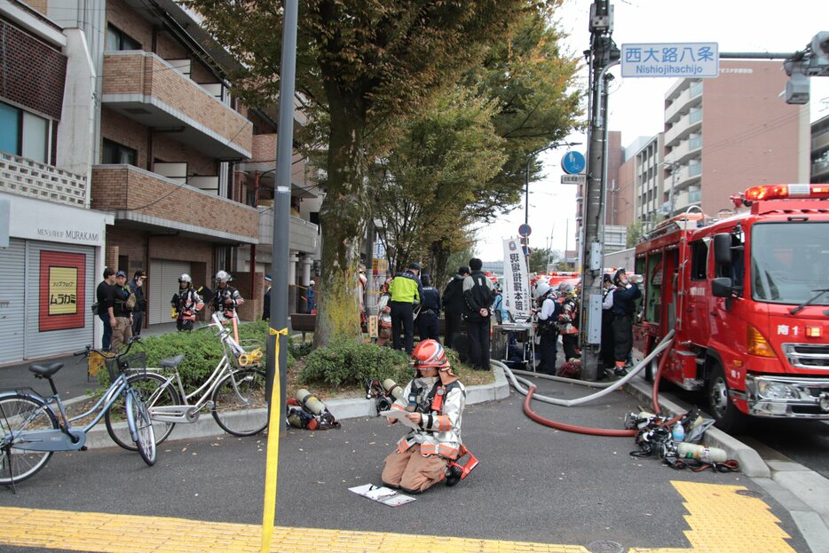 ９階で火災があったマンション前で活動する消防隊員ら（１５日午前１０時３１分、京都市下京区西大路通八条下ル）