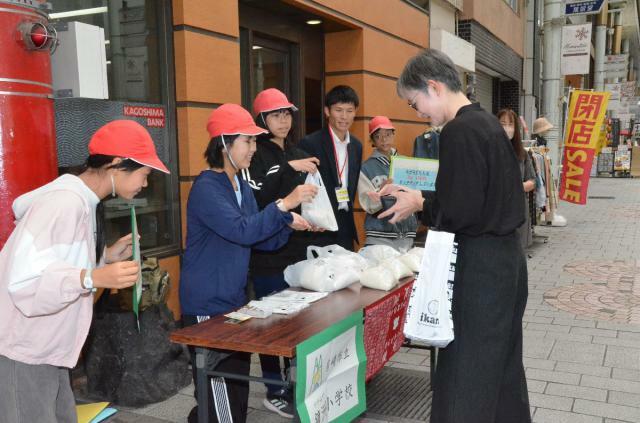 大事に育てた「かがみず米」を販売する鏡洲小の児童＝１４日、鹿児島市・天文館ぴらもーる（南日本新聞提供）