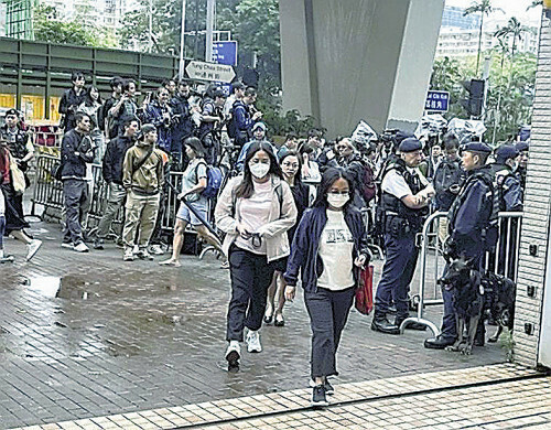 香港の裁判所で１９日、多数の警官が警戒する中、傍聴に向かう住民ら（手前）＝鈴木隆弘撮影