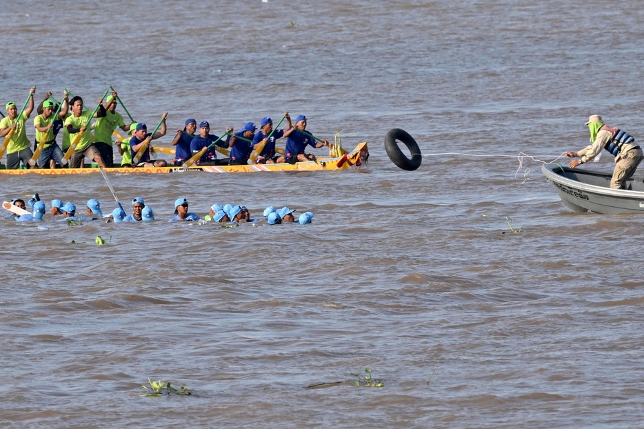 カンボジア・プノンペンを流れるトンレサップ川で開かれた水祭りで、競技中のドラゴンボートが沈み、参加者に浮具を投げる警察官（2024年11月14日撮影）。【翻訳編集】 AFPBB News