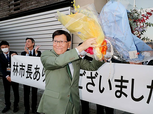 花束を掲げ、見送りの市民や市職員に感謝する林市長＝氷見市役所