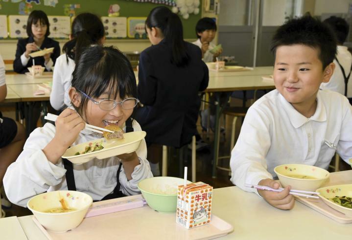 伊方町内産のイノシシ肉を使ったメンチカツを頬張る九町小の児童