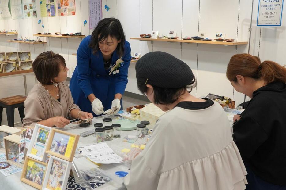 イケチョウガイの貝殻で時計を作る参加者と講師の大塚さん（写真左から2番目）