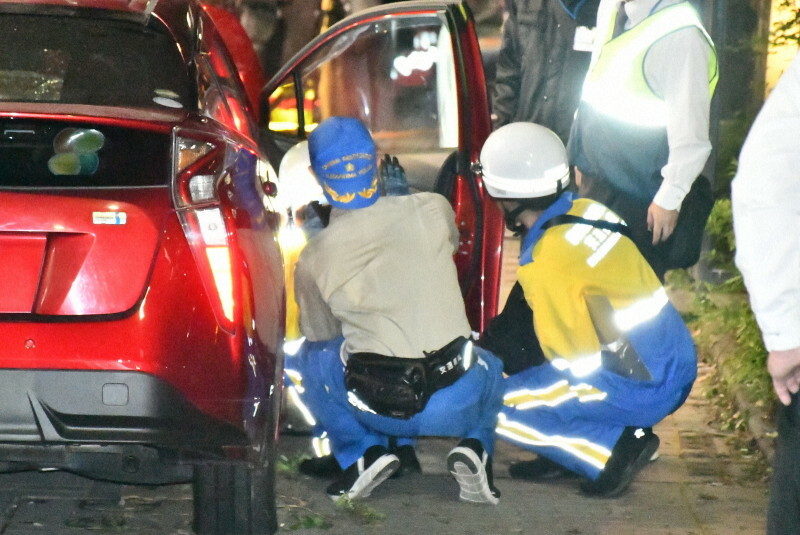 歩道に乗り上げた乗用車を調べる警察官＝鹿児島市下荒田1で2024年11月11日午後7時28分、取違剛撮影