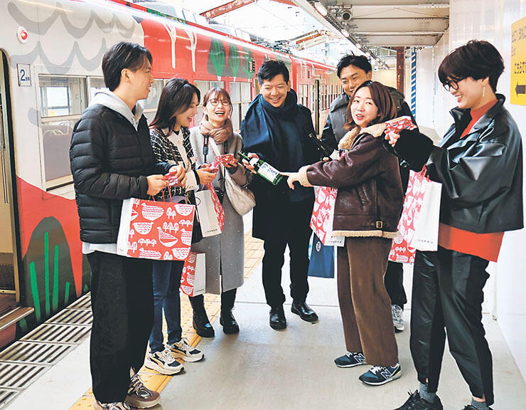 「富山もよう」を施した車両の前で地酒の魅力を語り合う参加者=電鉄富山駅