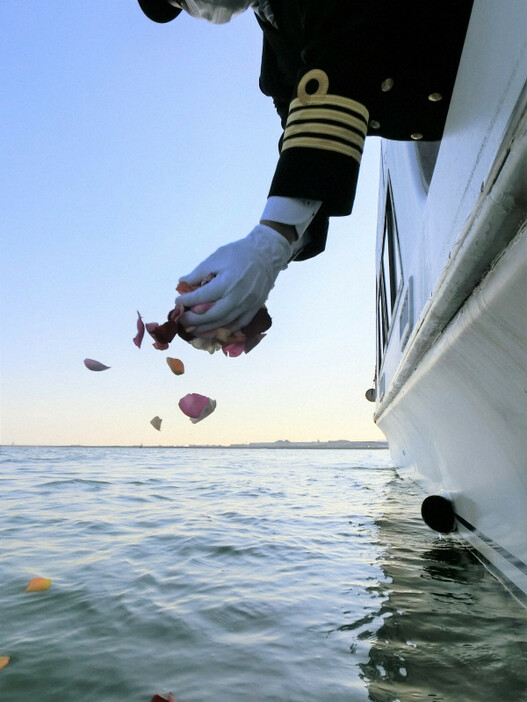 遺族に代わって散骨した後の海面に花びらを手向ける散骨会社のスタッフ＝ハウスボートクラブ提供