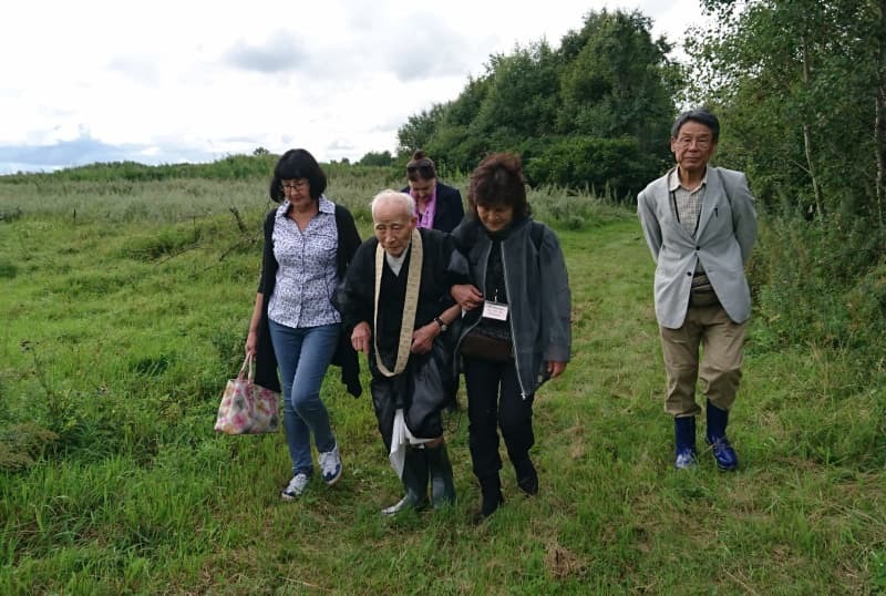 草むらをかき分け、日本人墓地を巡った横山周導さん＝２０１７年８月、ロシア極東アムール州