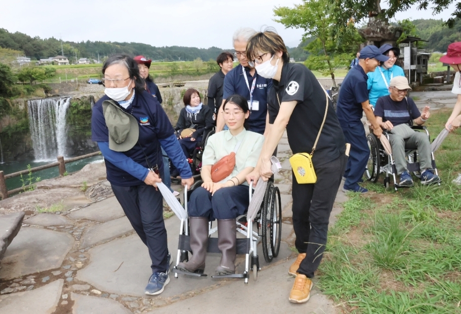 タオルを使って前輪を浮かせればスムーズに進むことを体験する参加者＝豊後大野市緒方町の原尻の滝