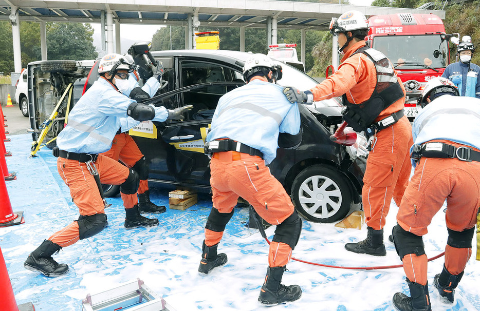 車内に閉じ込められた人を救助する訓練に取り組む消防隊員ら＝多気町丹生の伊勢自動車道勢和多気インターの作業ヤードで