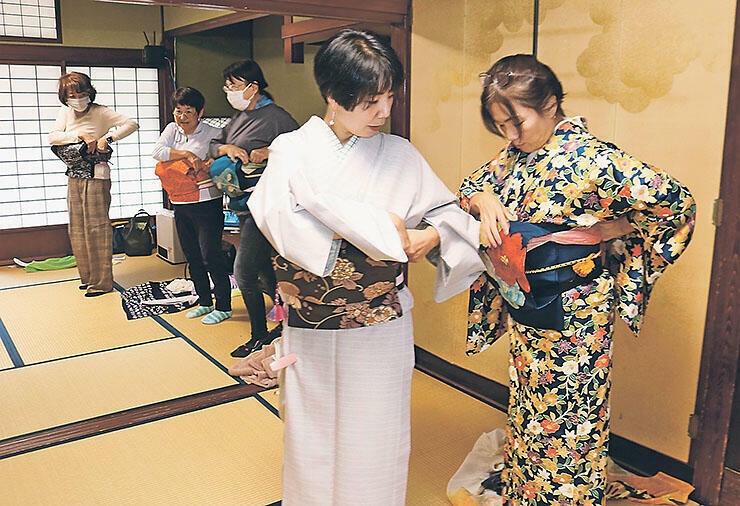 春木さん（右から2人目）から帯の結び方を習う参加者