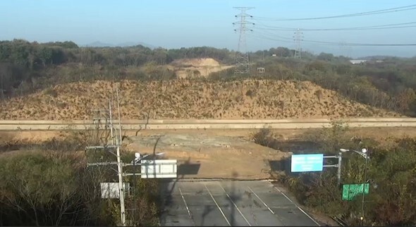 北朝鮮が南北連結道路の京義線を爆破した地点（道路標識の背後）。コンクリートに戦車を阻む穴が掘られ、土で壁が築かれている=合同参謀本部提供