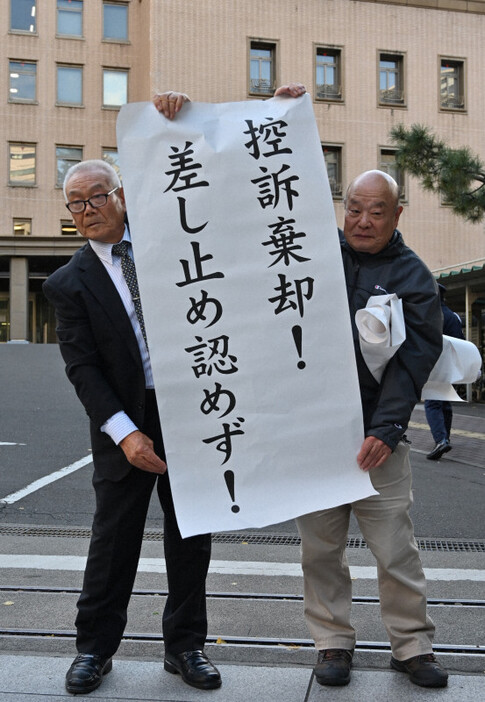 東北電力女川原発2号機の運転差し止めを求めた訴訟で控訴が棄却され、「差し止め認めず！」などと書かれた紙を掲げる原告団の佐藤清吾副団長（左）ら＝仙台市青葉区で2024年11月27日午後2時半、百武信幸撮影