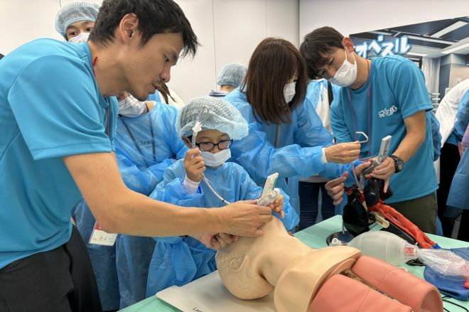 空気の通り道を確保する「気管挿管」を体験する子ども。イベントでは現役外科医が子どもたちに対応していました＝水野梓撮影