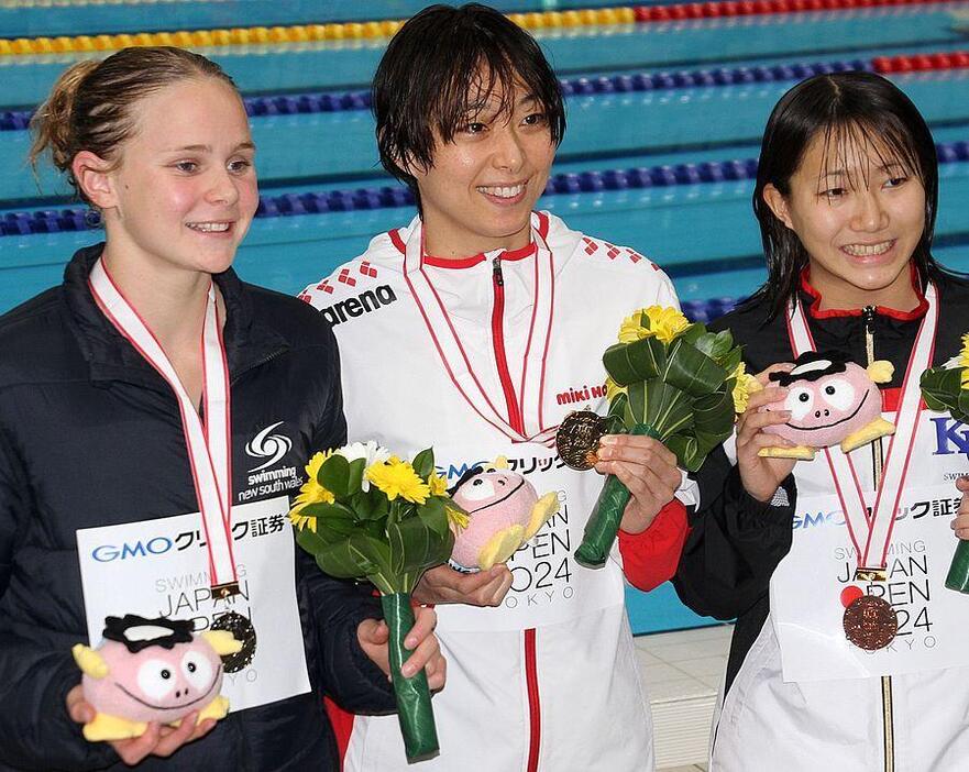 女子50メートル平泳ぎを制した鈴木（中）と2位のトーヒー（左）、3位の小畠