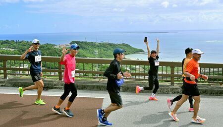 新里坂を上り切ると、そこは絶景の広がるニライカナイ橋。海に浮かぶ久高島を眺めながら尚巴志ハーフマラソンのランナーが駆け抜けていきました＝３日、南城市知念（竹尾智勇撮影）