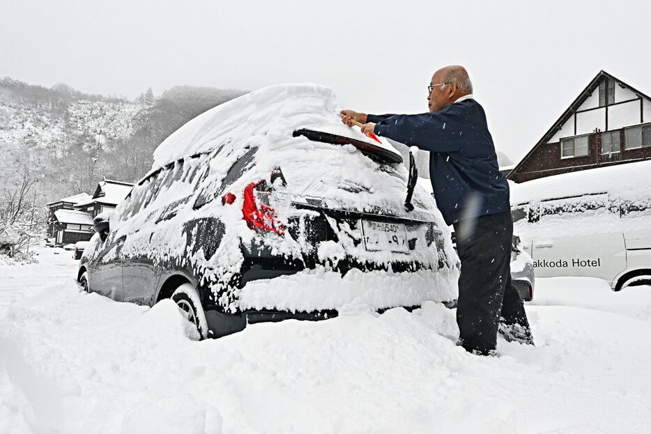 一日で積もった自家用車の雪を片付ける宿泊客＝7日午後、青森市の酸ケ湯温泉