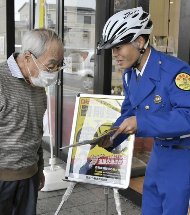 自転車のながら運転や酒気帯び運転への罰則について説明するバイシクルユニット隊員（右）＝1日午前、松山市松江町