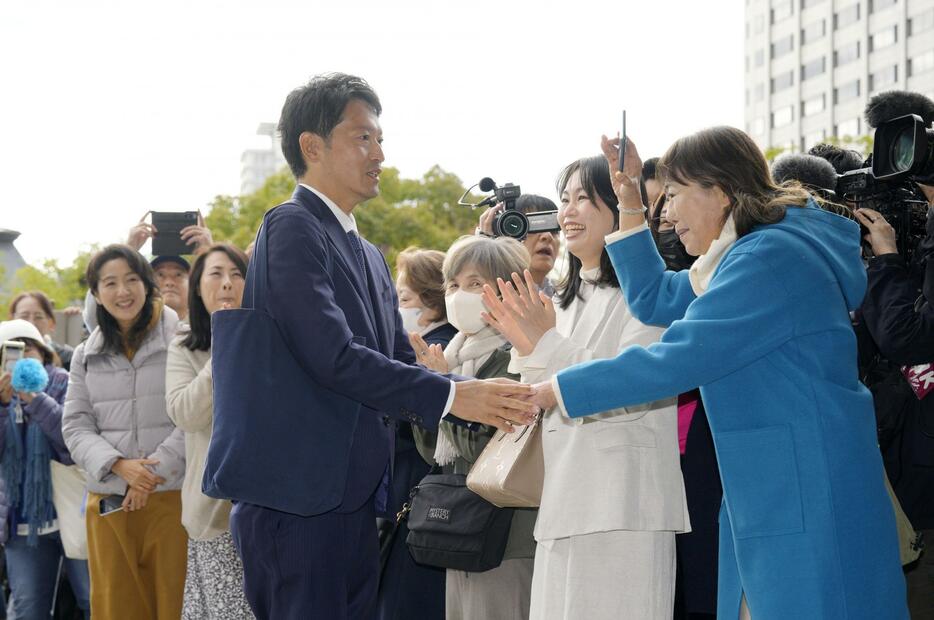 集まった支援者らに出迎えられ、兵庫県庁に登庁する斎藤元彦氏＝19日午前