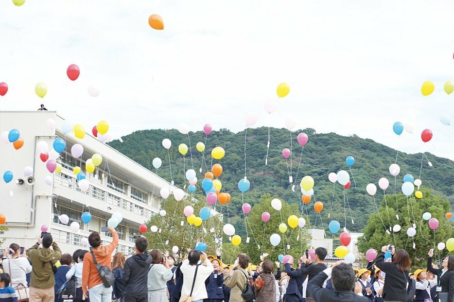 空撮のあと風船を飛ばして祝う参加者ら