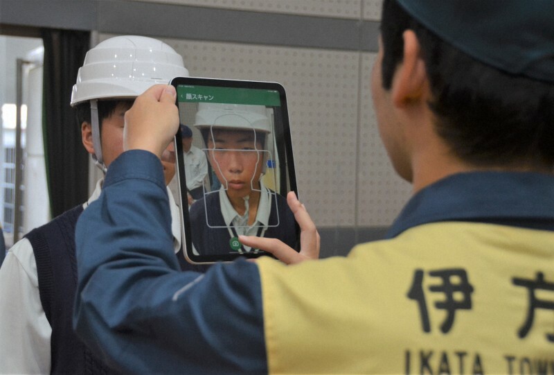 愛媛県の原子力防災訓練で、愛媛県伊方町の集団避難の一時集結所で顔認証で受け付けを行う高校生＝同町の三崎総合体育館で2024年、山中宏之撮影