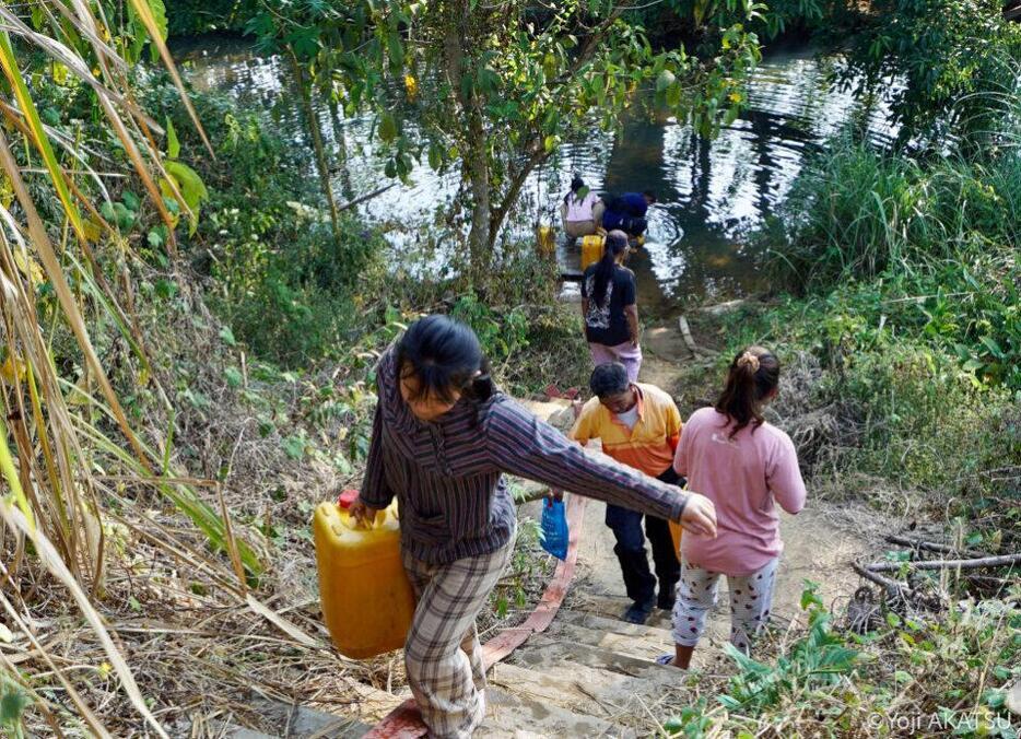 近くの川から水を汲むカレンニー州警察の警官たち。メーセ町内には上水道が整備されていたが、現在は機能しておらず、炊事・洗濯のために毎日水を汲み、運ばなければならない。（2024年2月、ミャンマー・カレンニー州メーセ、撮影：赤津陽治）