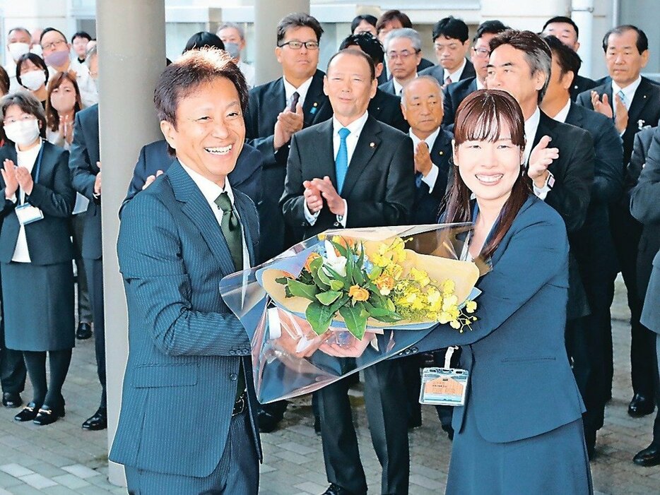 初登庁し、職員から花束を受け取る菊地市長（手前左）＝氷見市役所