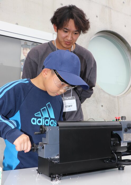 卓上旋盤を使い、真剣な表情でこまを作る子ども（久御山町森・クロスピアくみやま）