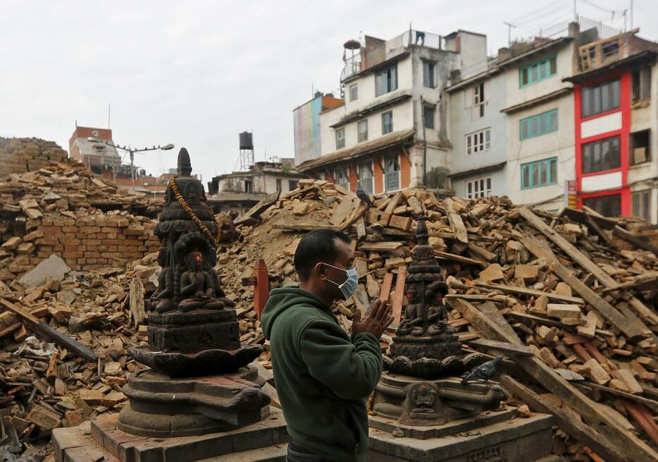 倒壊した寺院で祈る男性＝2015年4月28日（写真：ロイター/アフロ）